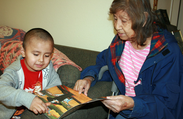 Native American child with books reading with his grandmother