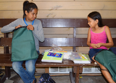 A photo of two students, Eliza and Evoni, receiving school supplies